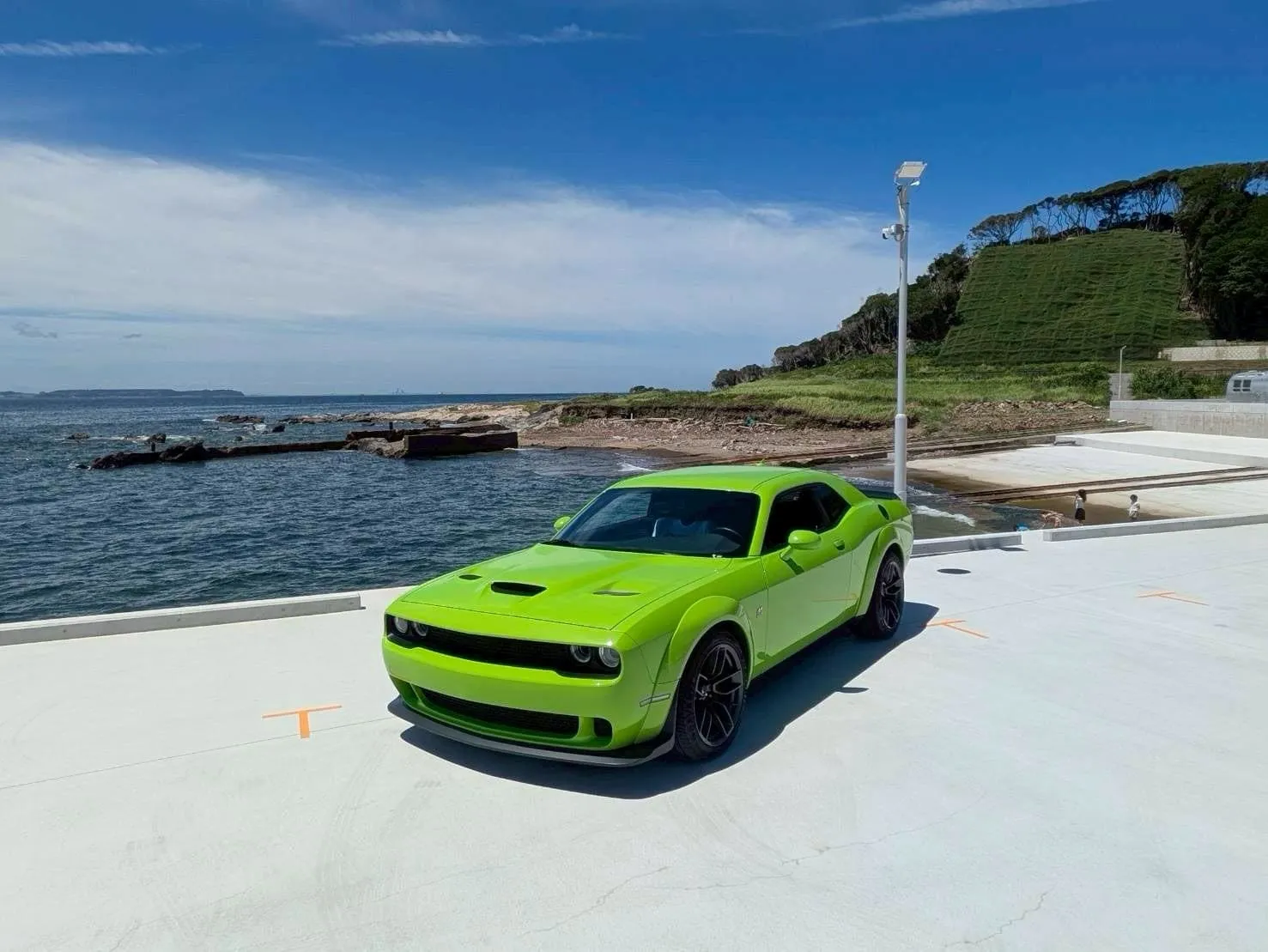 海沿いのスロープに停めたスポーツカーと東京湾