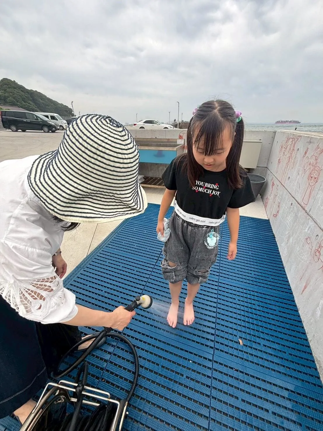 屋外の手洗い場で足を洗う女の子