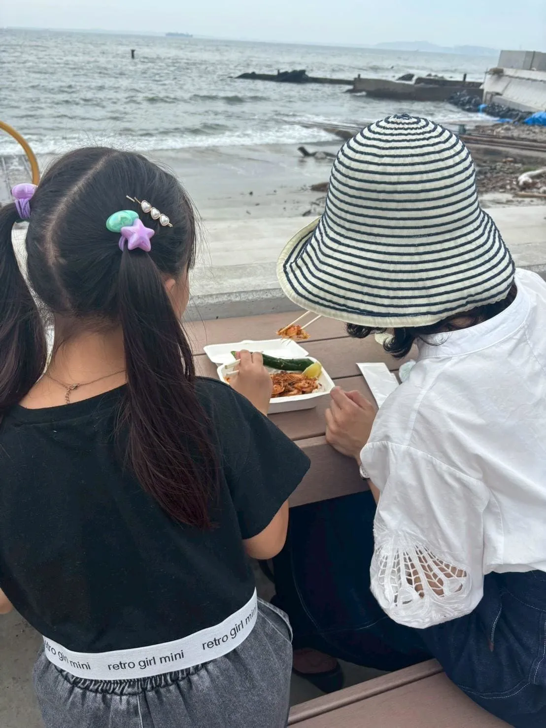 海を眺めながらガーリックシュリンプを食べる親子