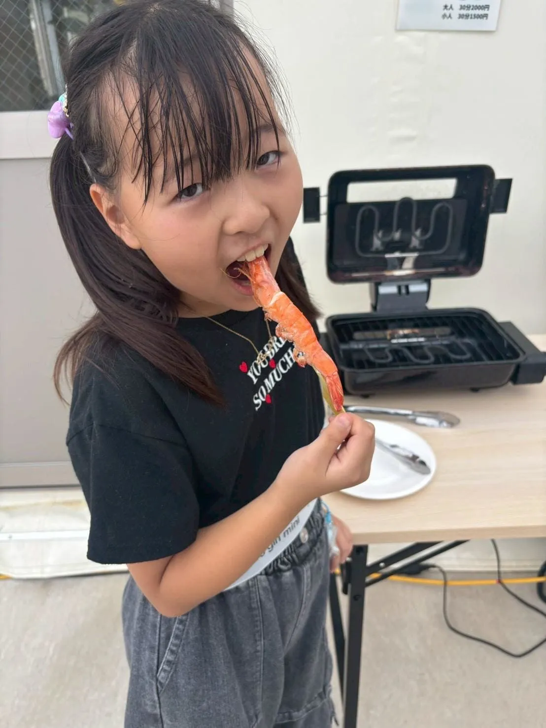 釣ったエビをグリルで焼いて食べる女の子